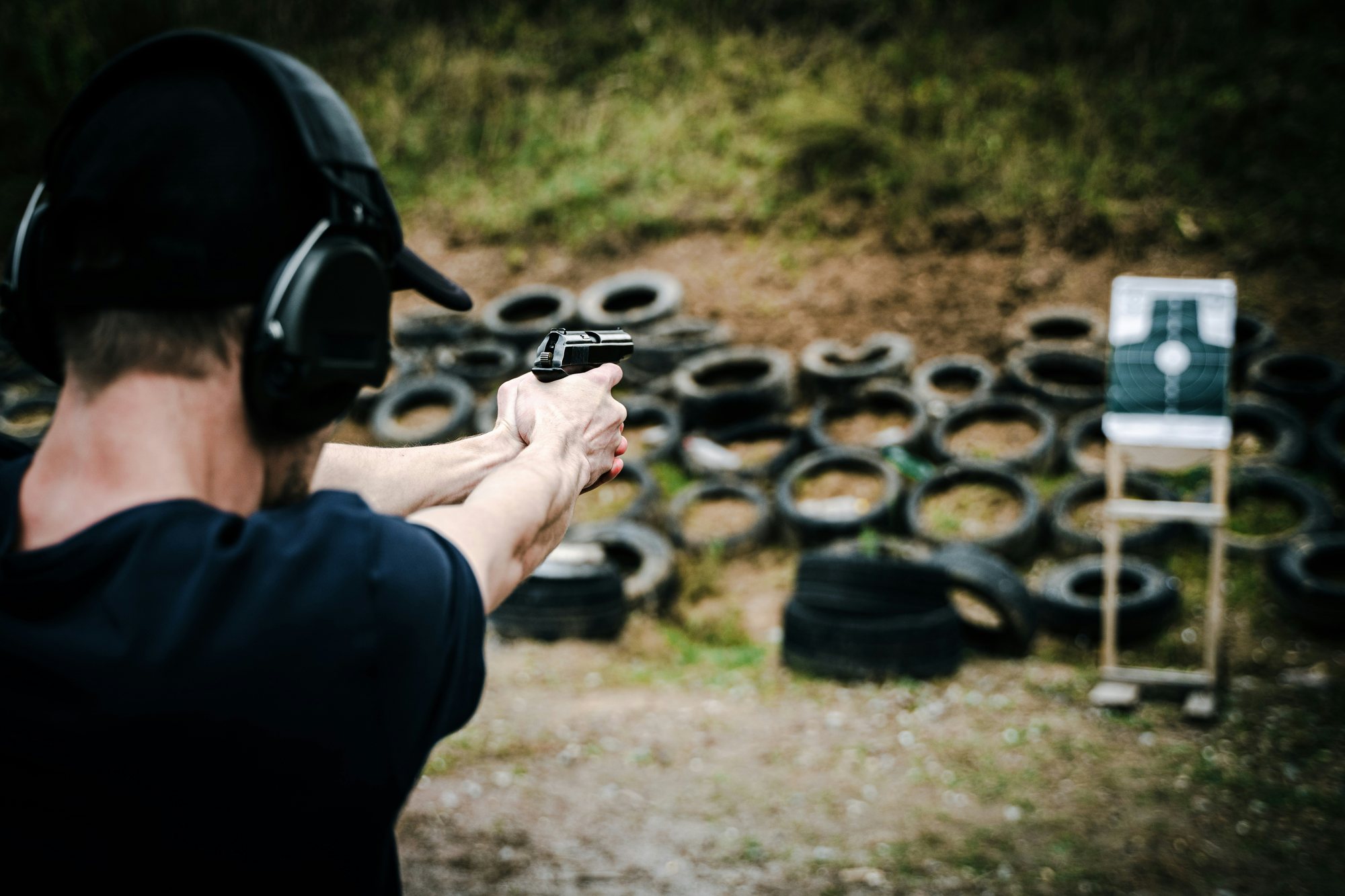 A shooter firing a pistol at targets on an outdoor range during a New Jersey concealed carry qualification