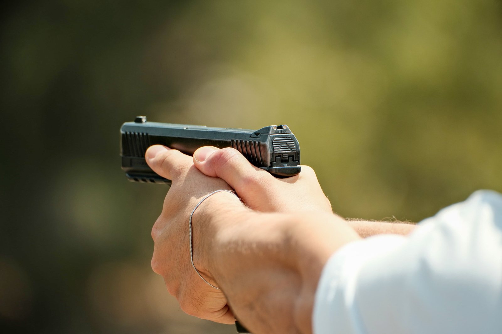 A steady two-handed grip on a pistol at an outdoor range
